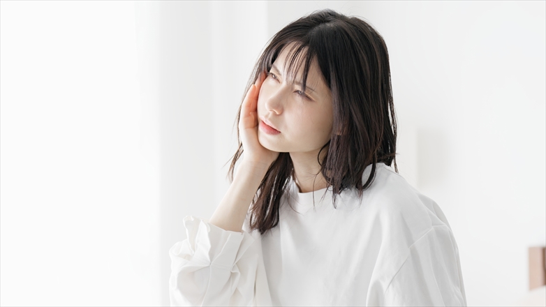めまいがしてこめかみを押さえる女性